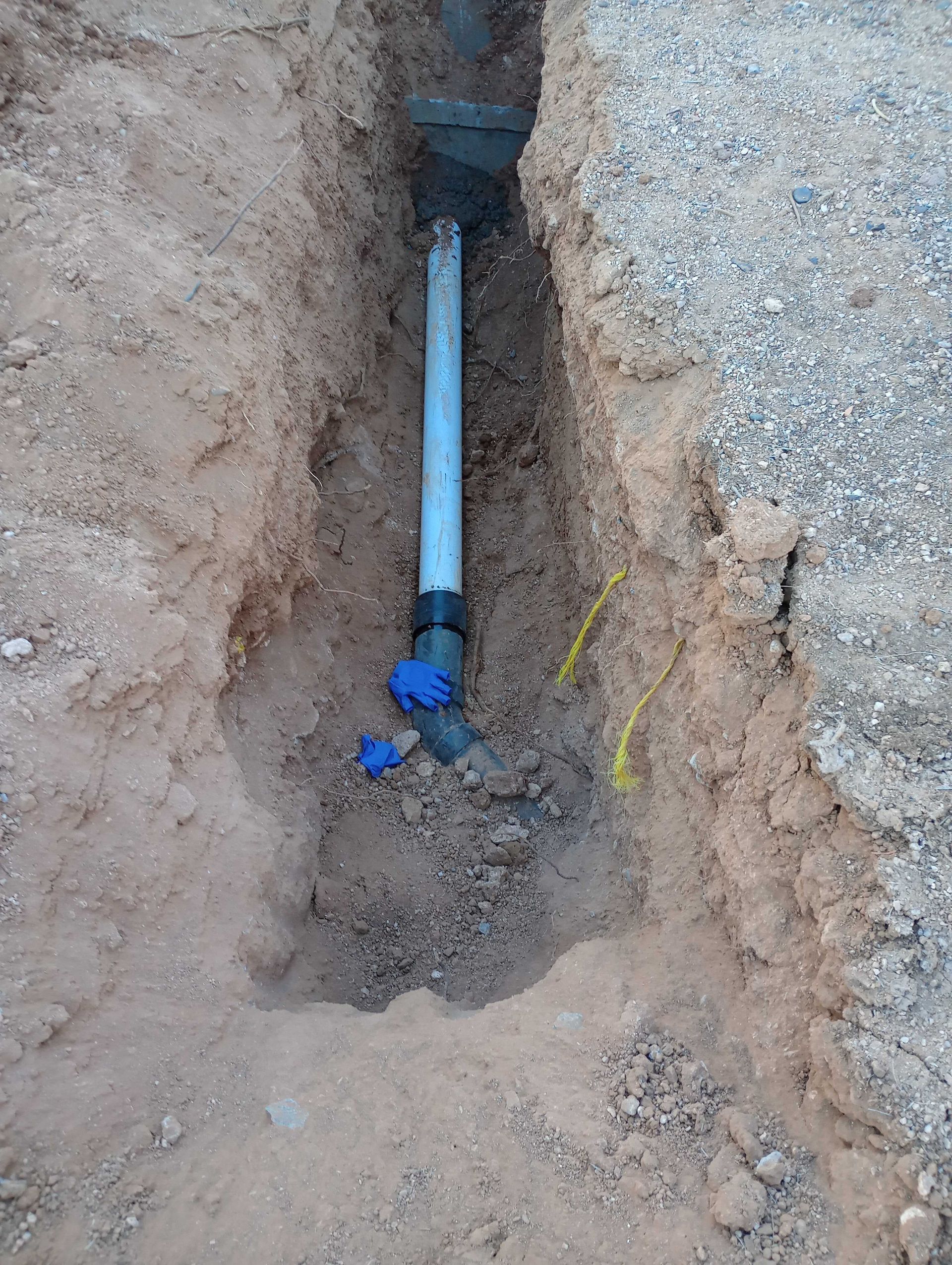 Three black septic tanks installed in an excavated pit; orange pipe visible.