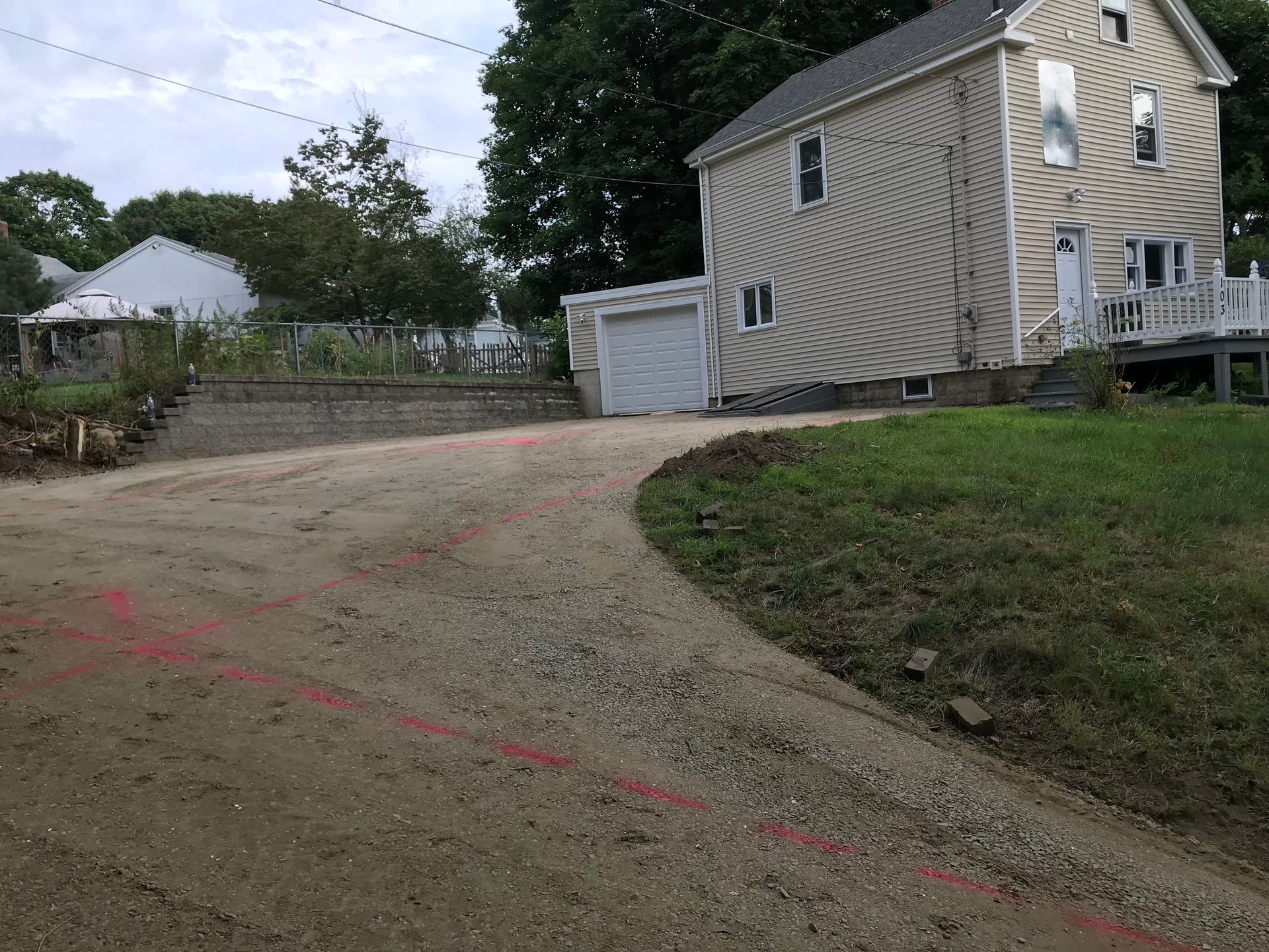 A house is sitting on top of a grassy hill next to a dirt road.