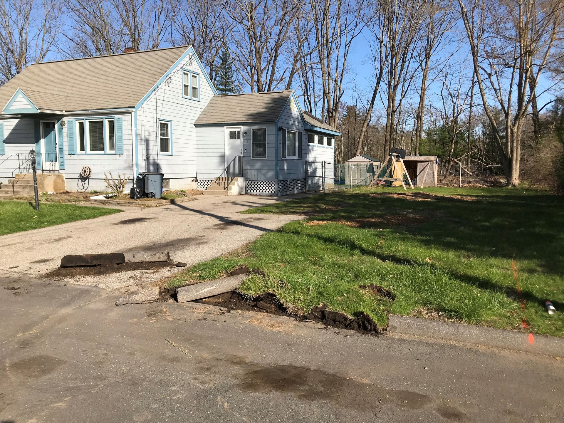 A white house with a brown roof is sitting on top of a lush green field.