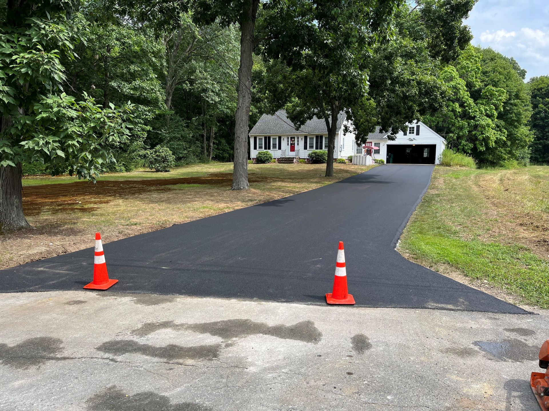 A driveway with two orange cones on it in front of a house.