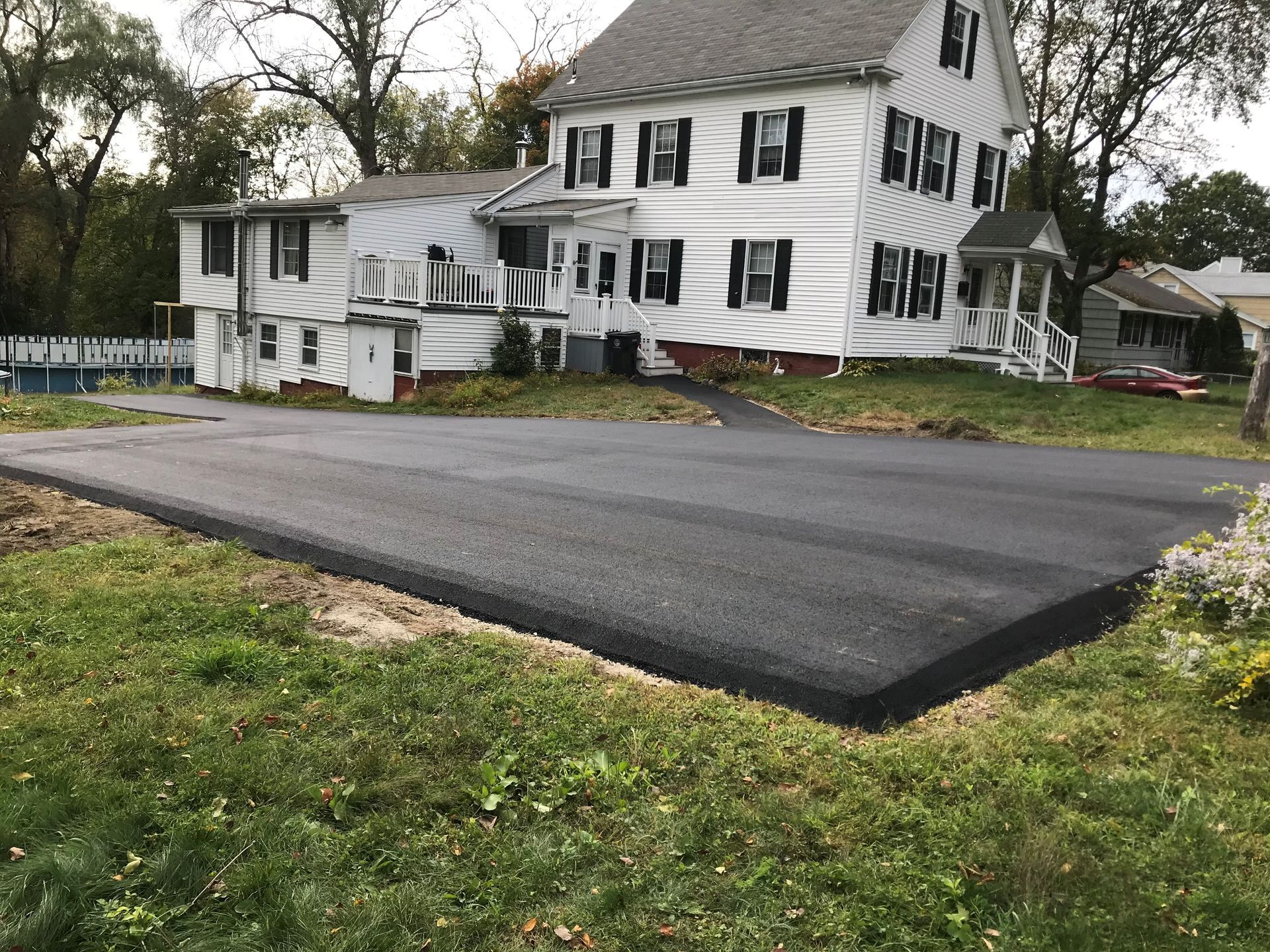 A large white house with a black driveway in front of it.