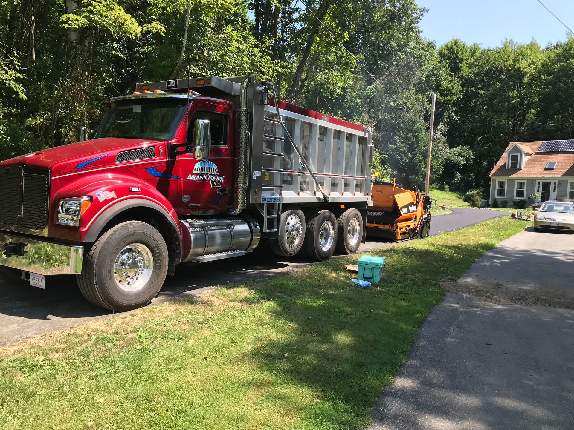 A red dump truck is parked on the side of the road next to a house.