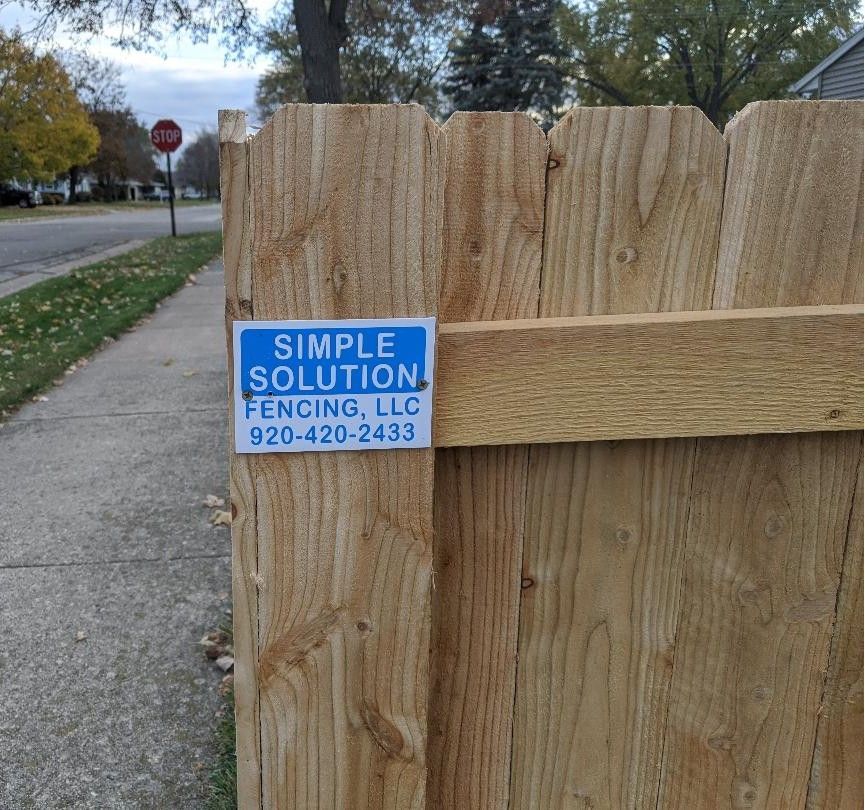 Wooden fence with a blue sign that says 