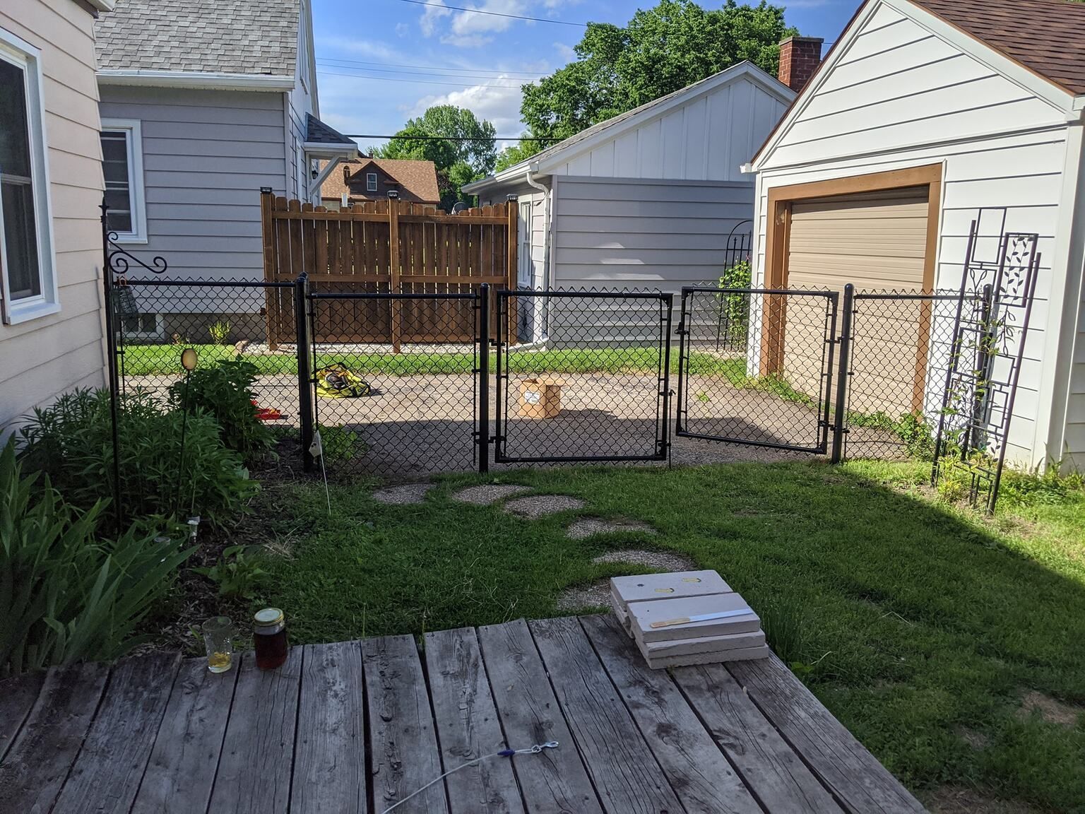 Backyard with wooden deck, chain-link and wooden fences, small garden, and a garage.