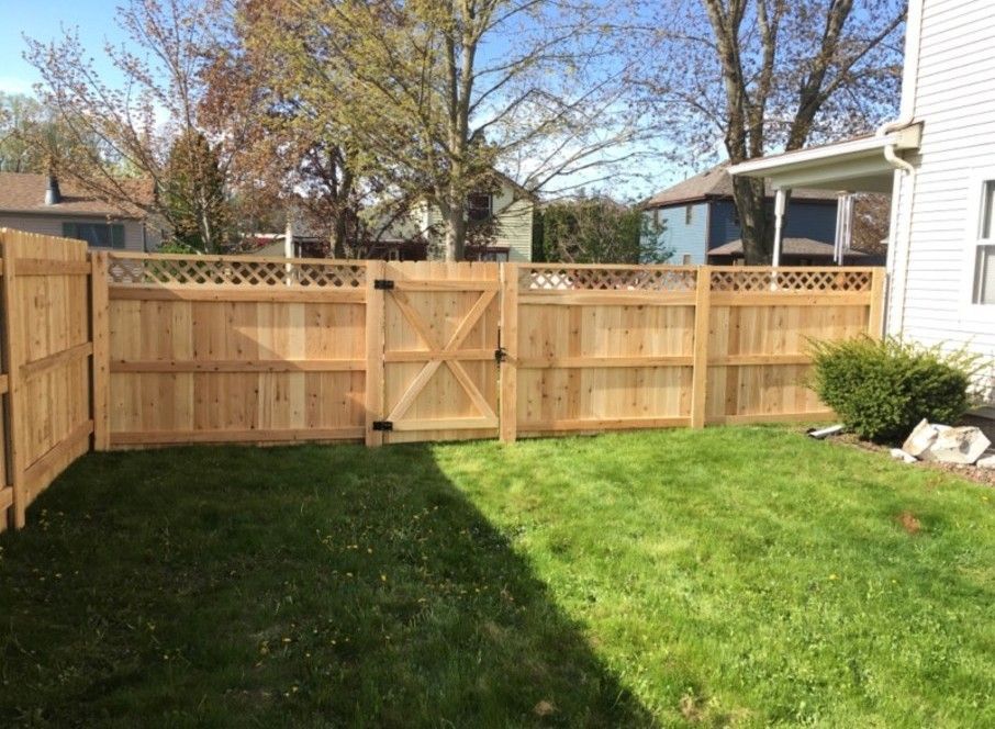 Wooden fence with gate in grassy backyard.