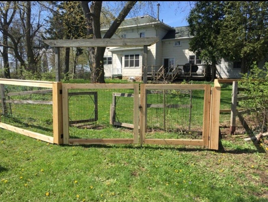 Wooden fence with gate in front of a white house.