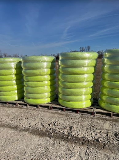 A bunch of green tubes are stacked on top of each other on a wooden pallet.
