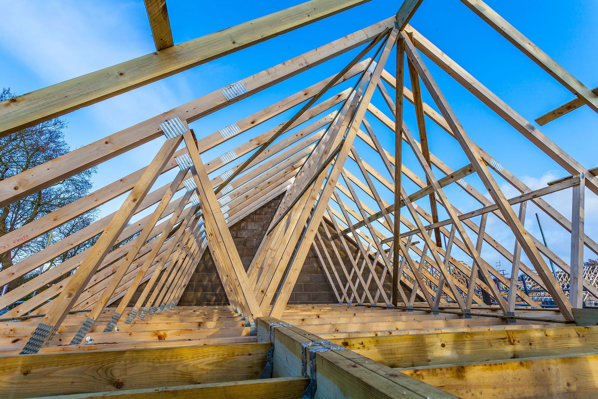 Wooden roof trusses under construction against a clear blue sky