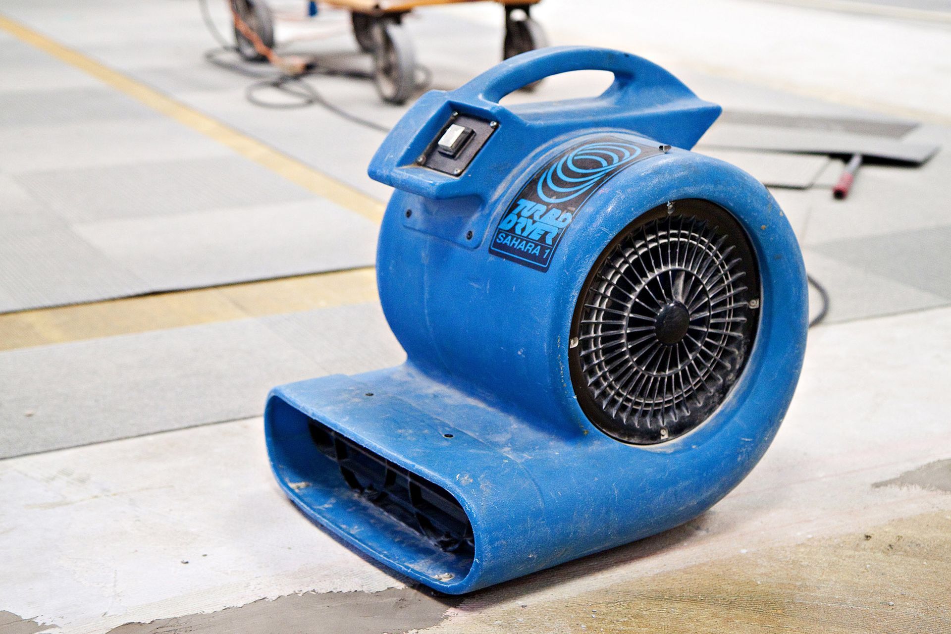 Blue industrial floor blower fan in a workshop or garage