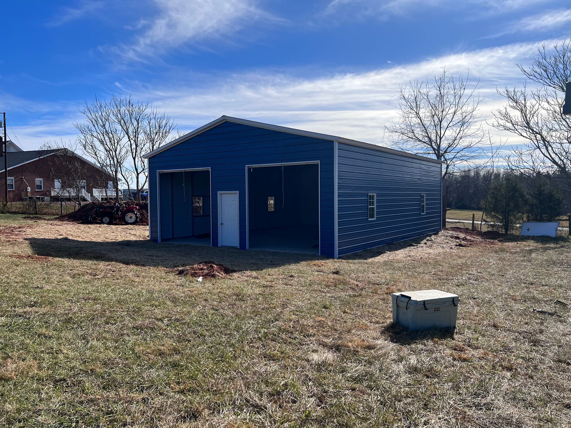 Blue metal shed in a grassy field under a clear sky