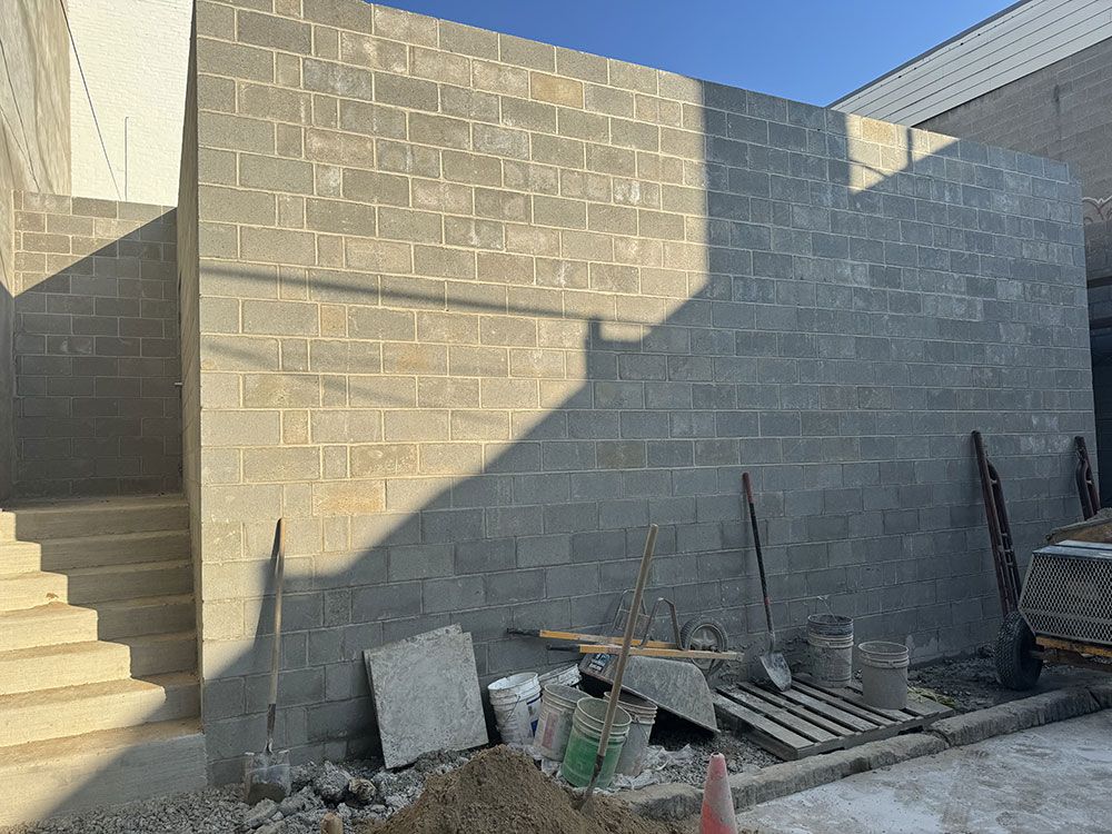 Construction site with unfinished gray cinder block walls and stairs. Tools and materials are in the foreground.