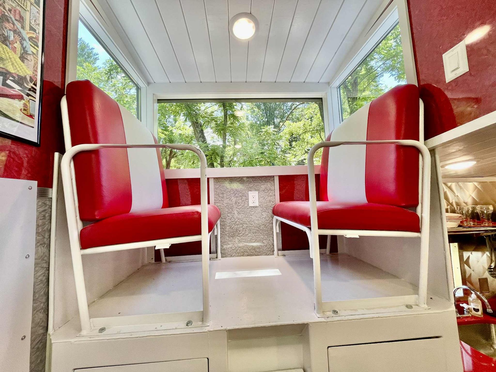 Interior of a red and white vehicle with two seats, a window, and a light.
