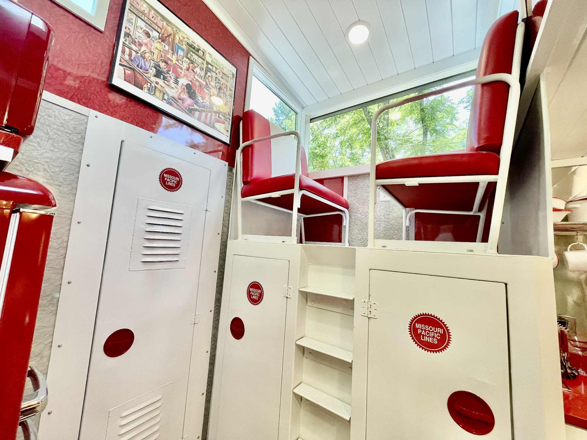 Red and white diner booth seating; red seats, white frames, with a picture on the wall.