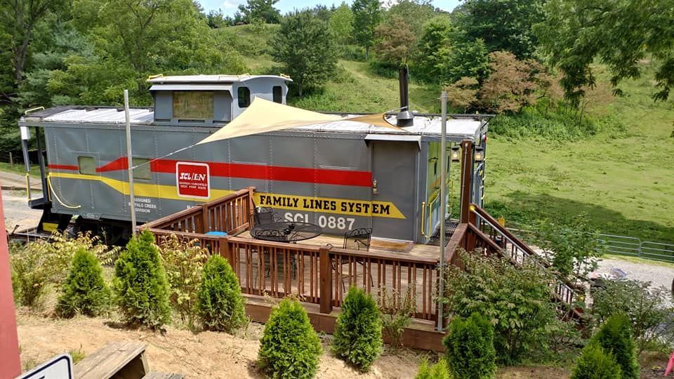 Caboose converted into building with deck; gray, red and yellow paint.