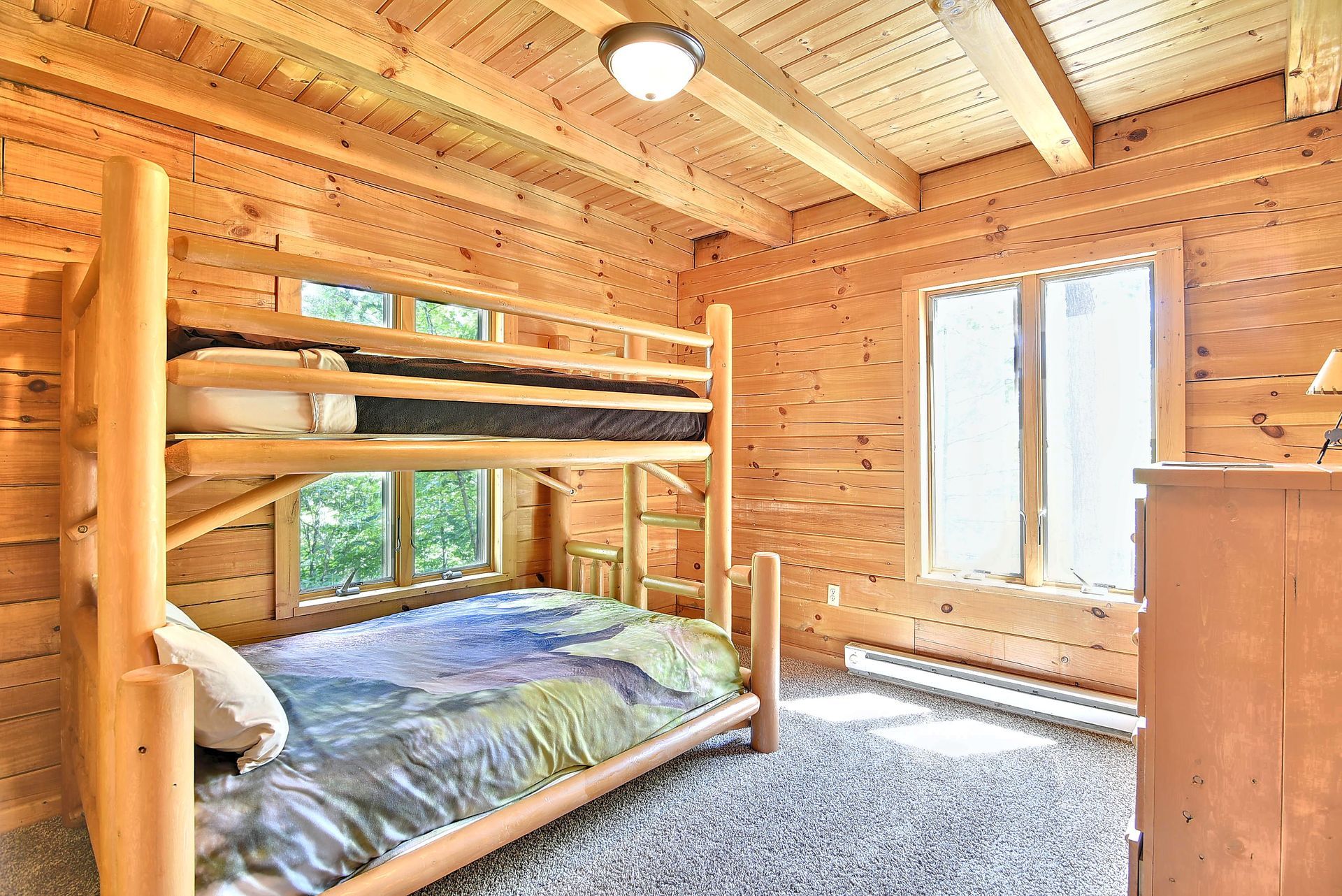Bunk beds in a wood-paneled room with a window, carpet, and a light fixture.