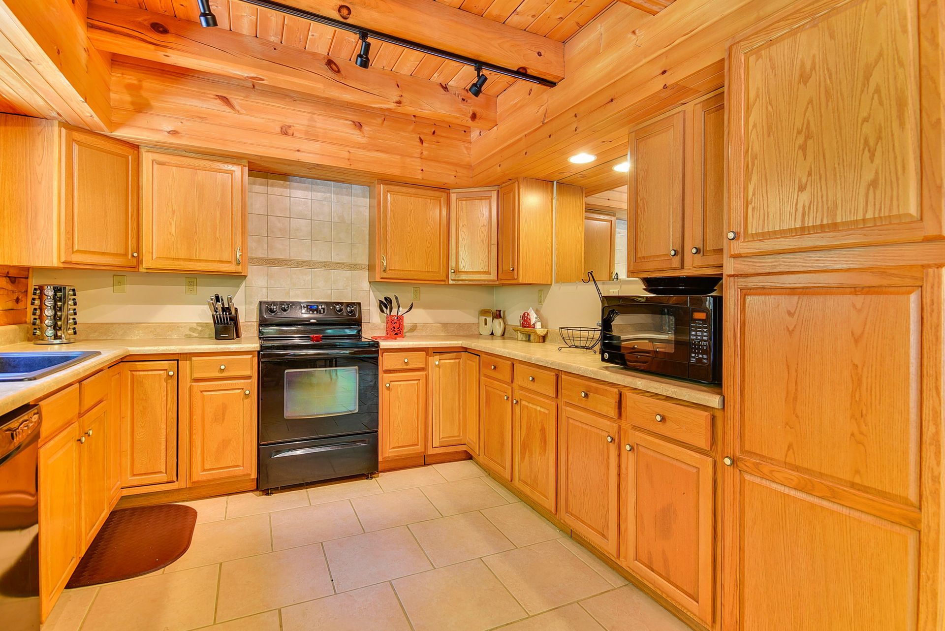 Wooden kitchen with cabinets, stove, and microwave.