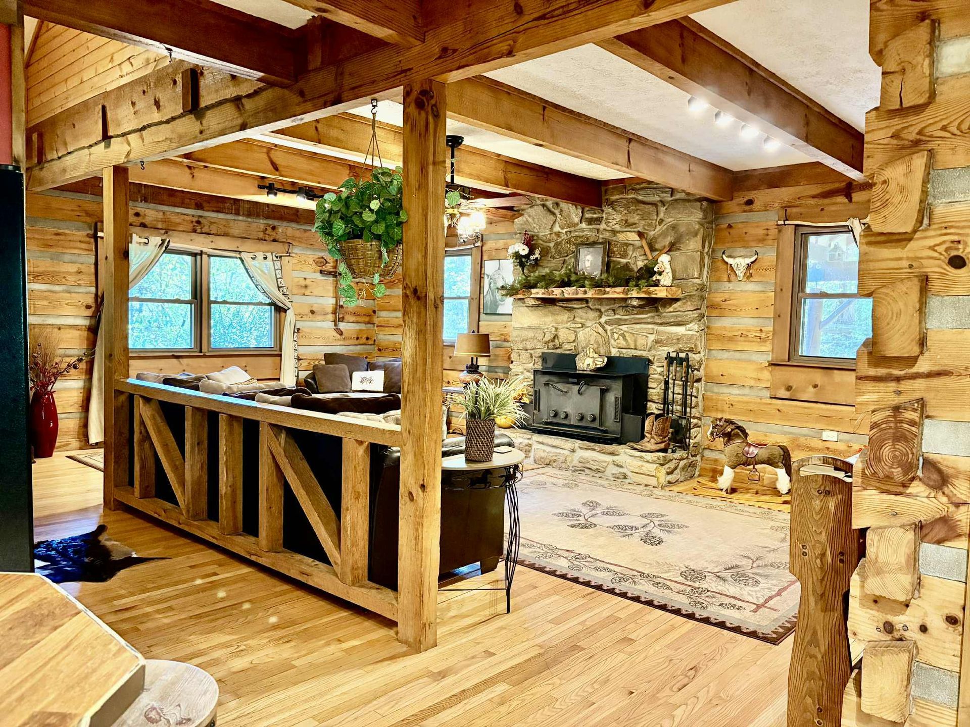 Rustic cabin interior with wood beams and stone fireplace.