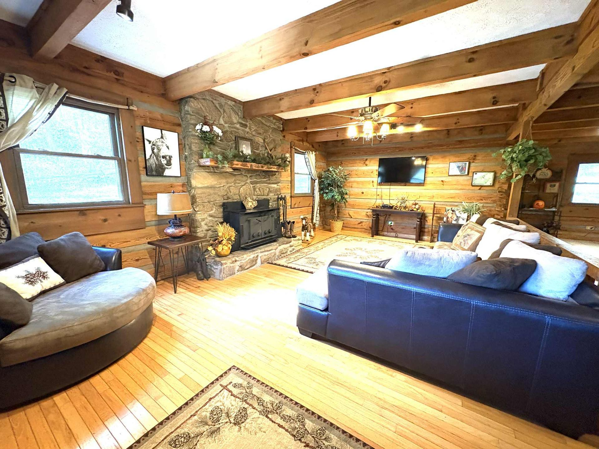 Rustic living room with wood beams, stone fireplace, and leather furniture.