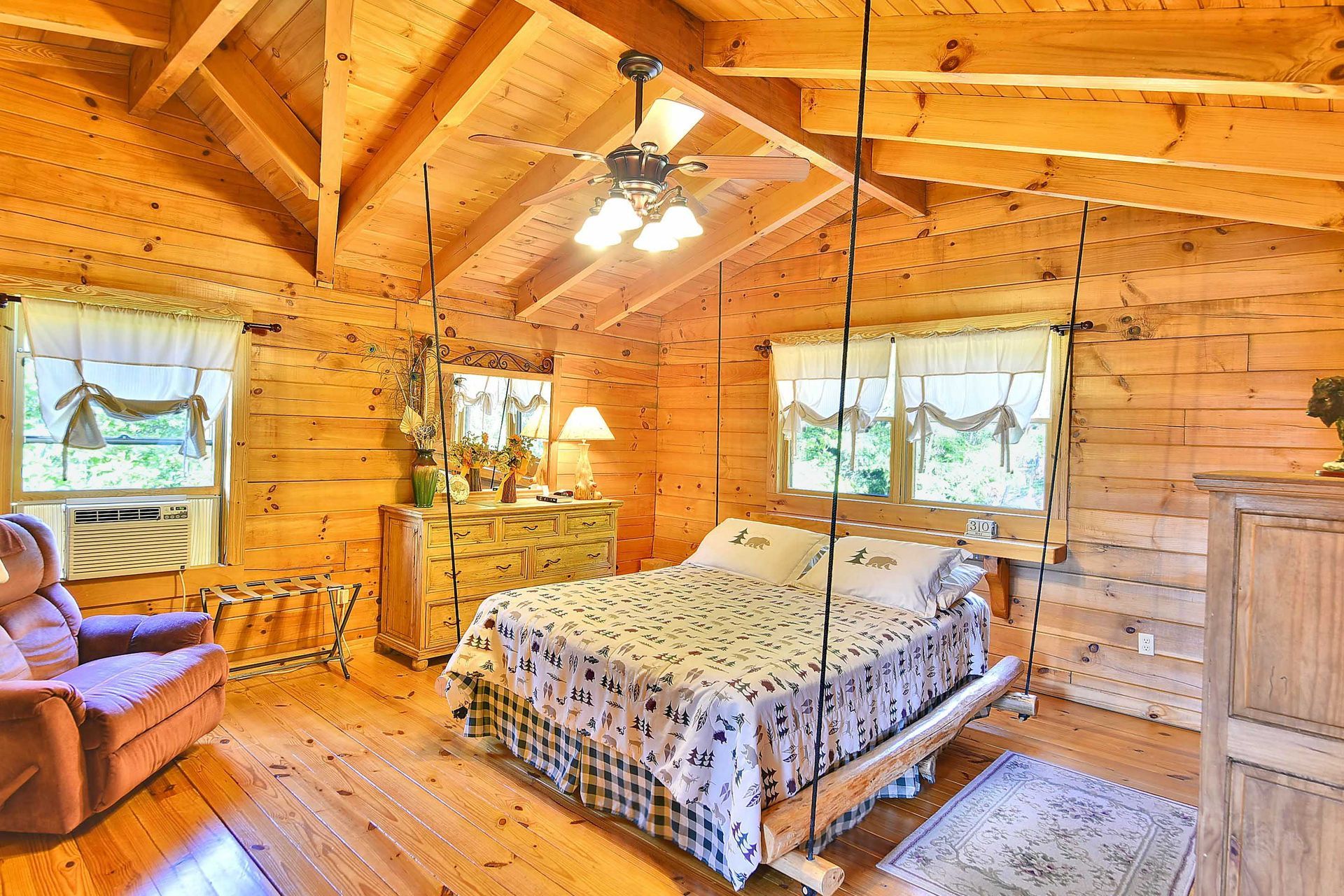 Cozy bedroom with wooden walls, vaulted ceiling, and a swing bed.