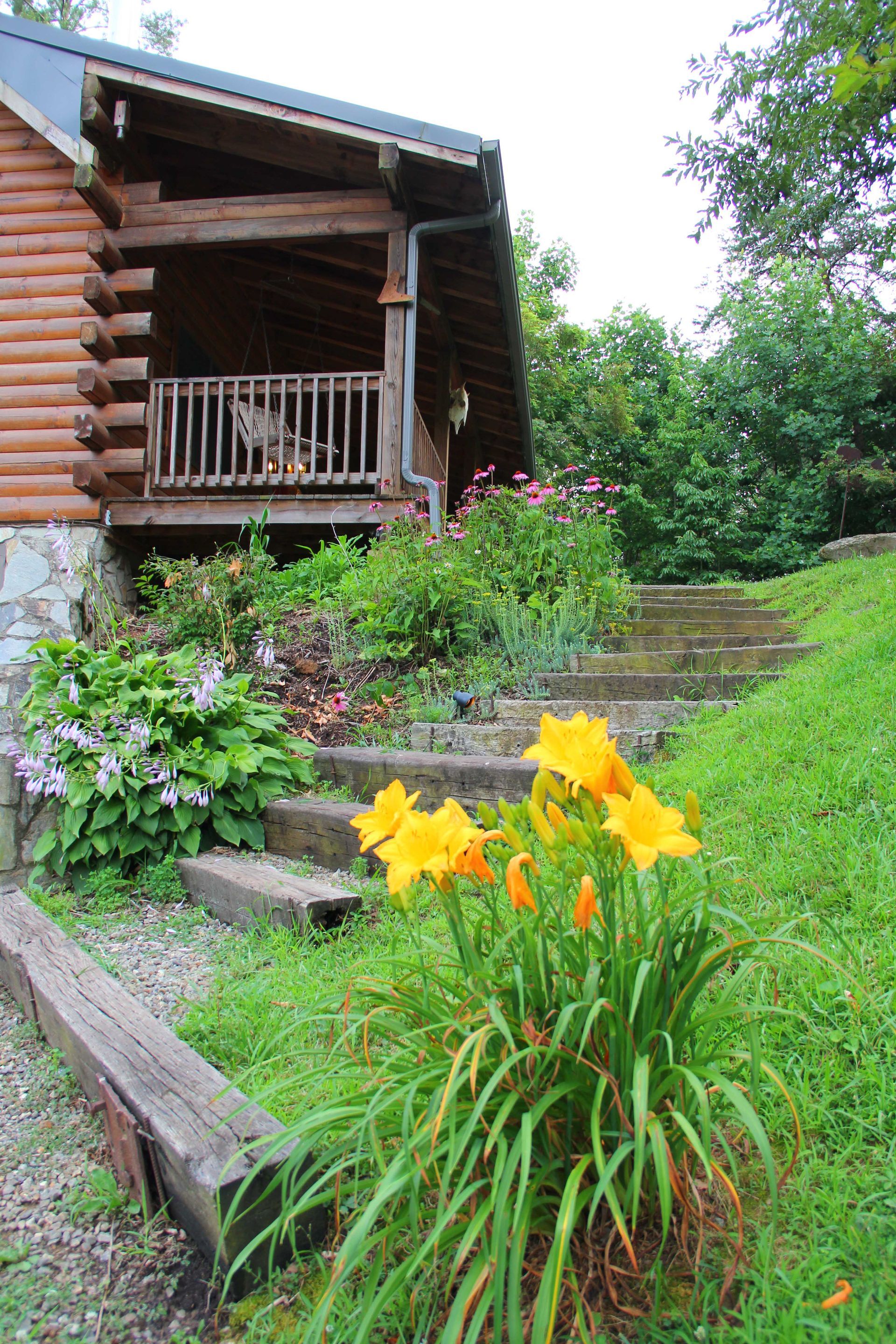 Log cabin with wooden steps, yellow flowers, and a small porch.