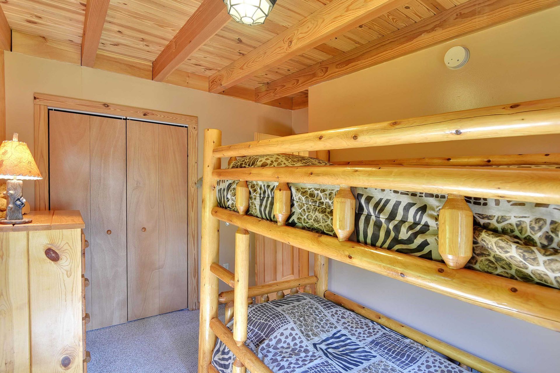 Rustic bedroom with bunk beds made of logs and a wooden closet.