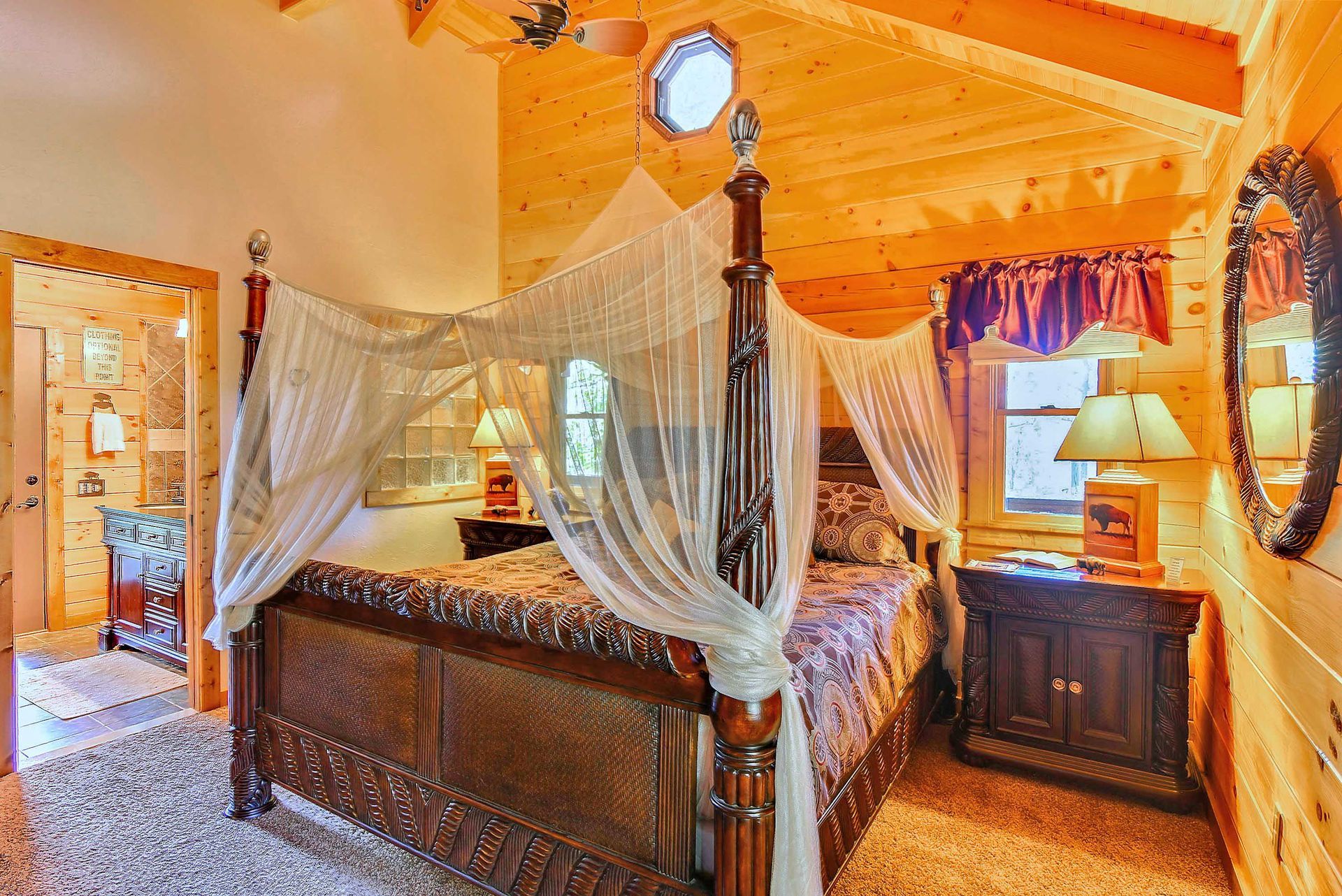Cozy bedroom with canopy bed, wooden walls, porthole window, and antique furniture.