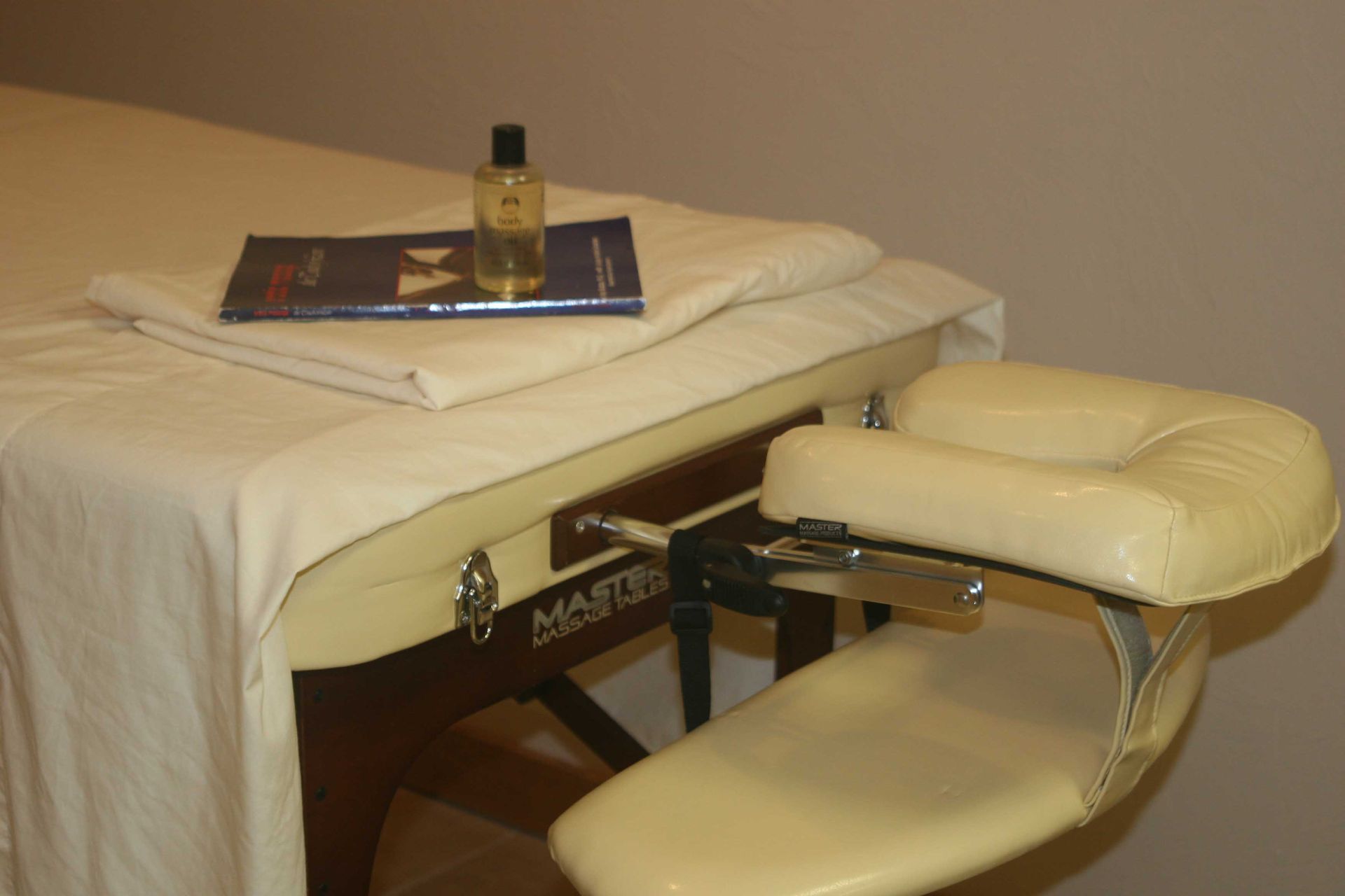 Massage table set up with oil, booklet, and arm rest.