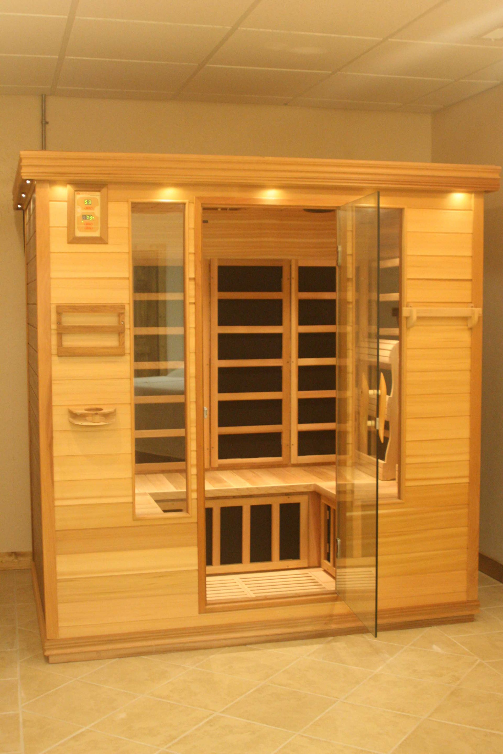 Wooden sauna with glass doors, interior view of seats and infrared panels.