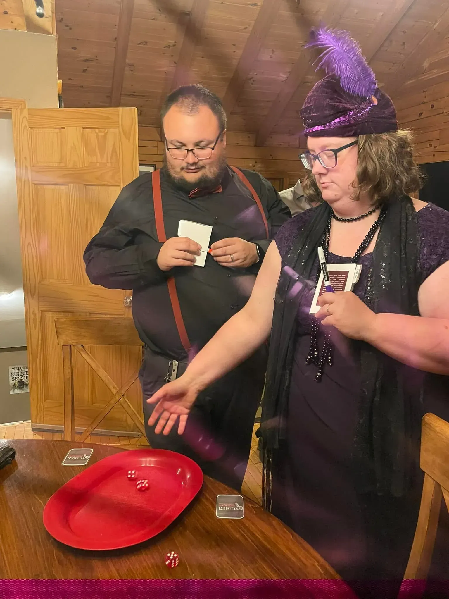 Two people in costume playing a dice game. Woman in purple, is rolling dice, man looking on.