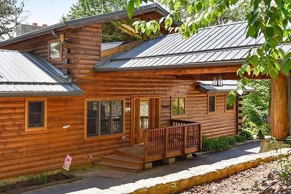 Wooden log cabin house with a covered entryway and metal roof.