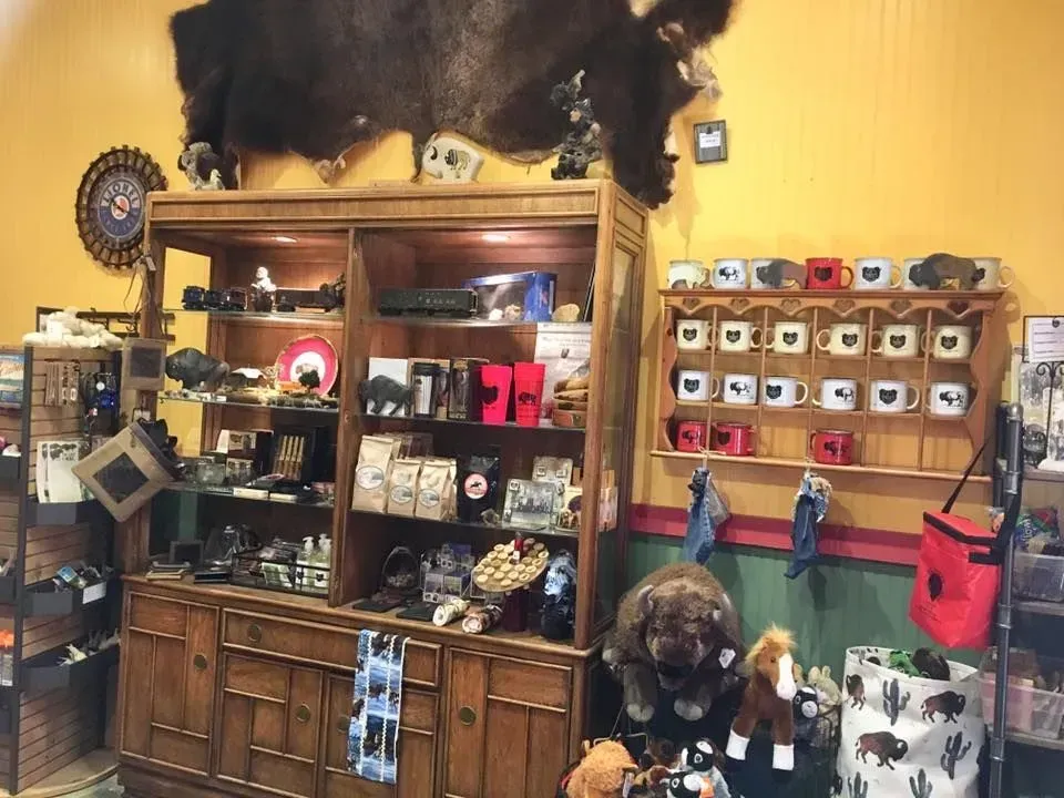 Inside a gift shop with bison-themed merchandise, mugs, stuffed animals, and a buffalo hide.