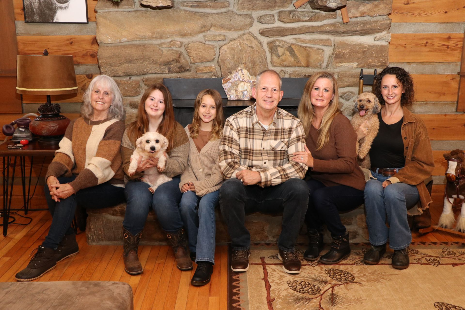 Family of seven poses in front of a stone fireplace; two women hold dogs.