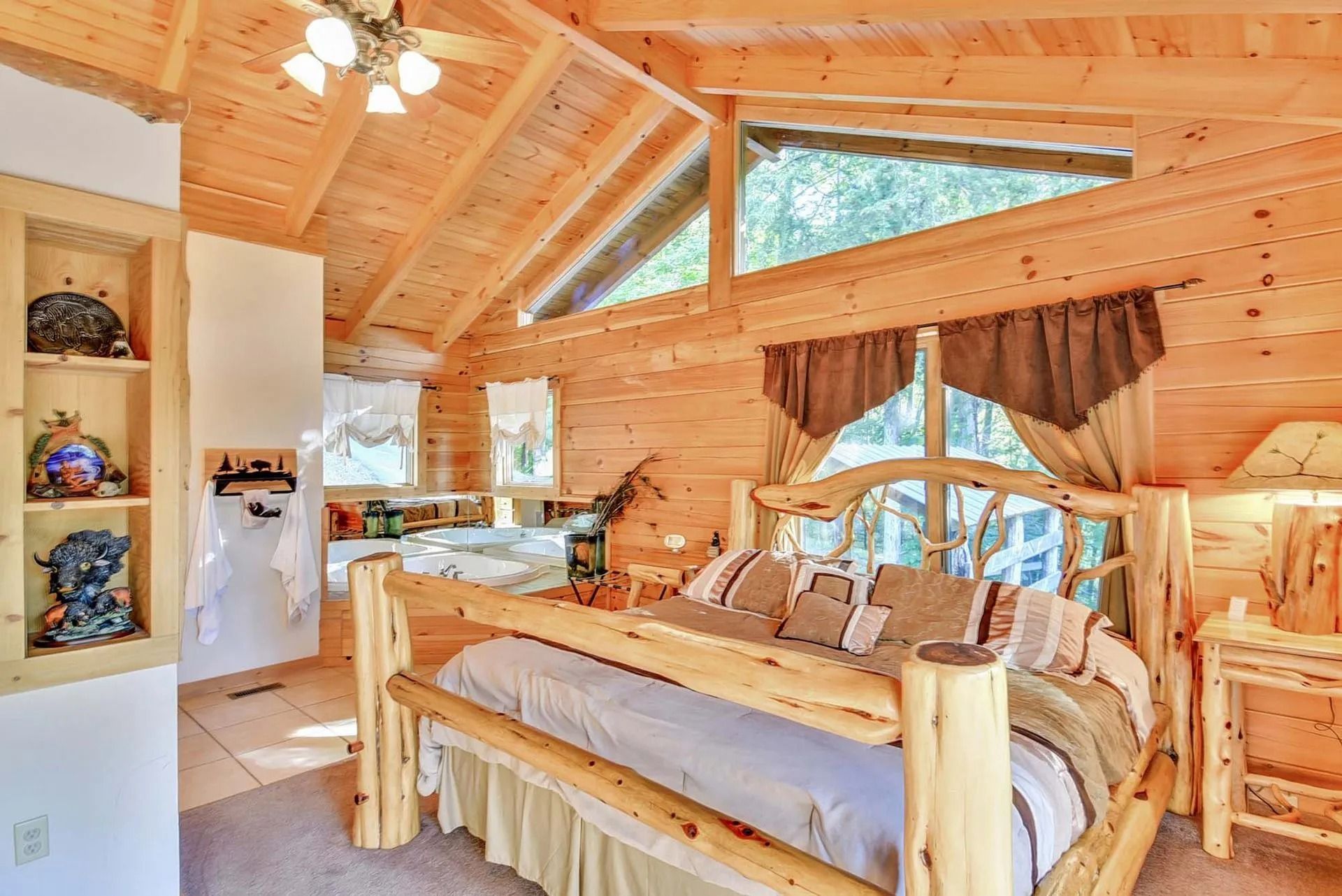 Wooden bedroom with log bed, open to a spa-like bathroom, bright with natural light.