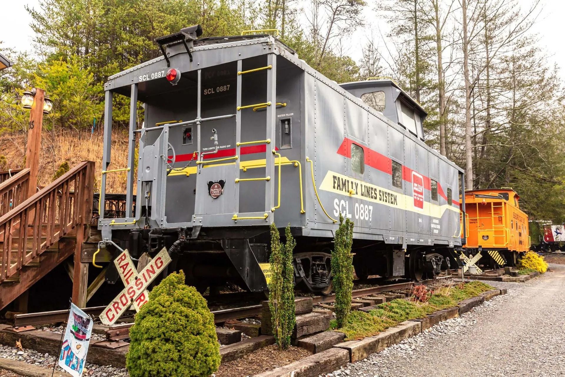Gray caboose with red and yellow accents on display outdoors, labeled