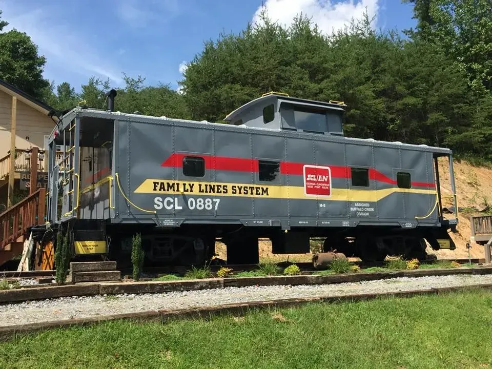 Gray and red caboose on tracks, labeled