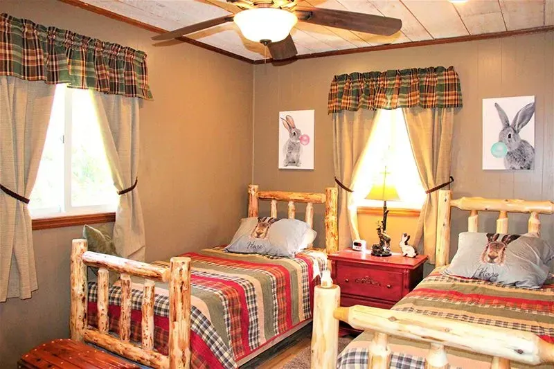 Two rustic twin beds in a cabin-style room with plaid bedding and bunny art.