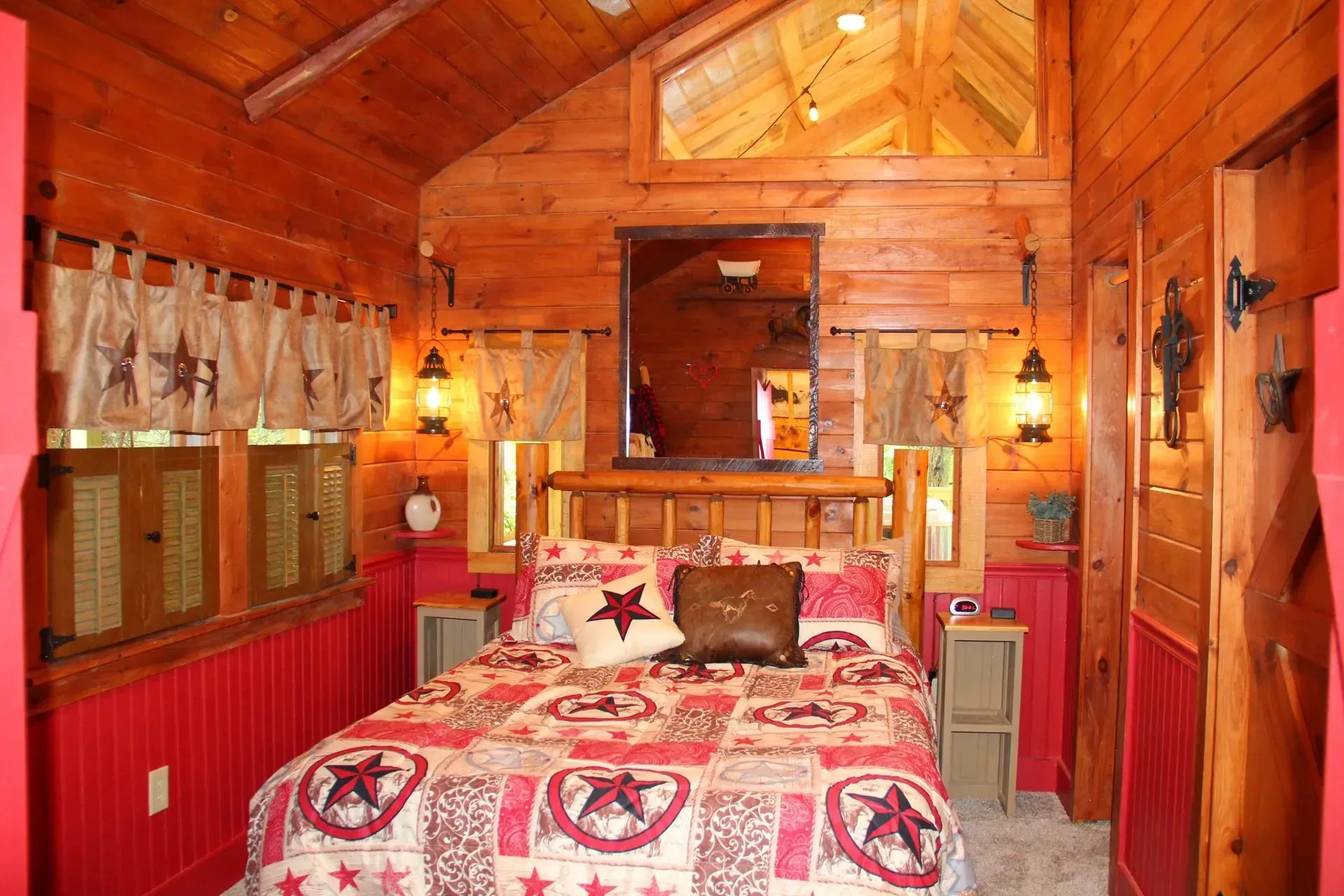 Rustic bedroom with red accents, wooden walls, and country-themed bedding.