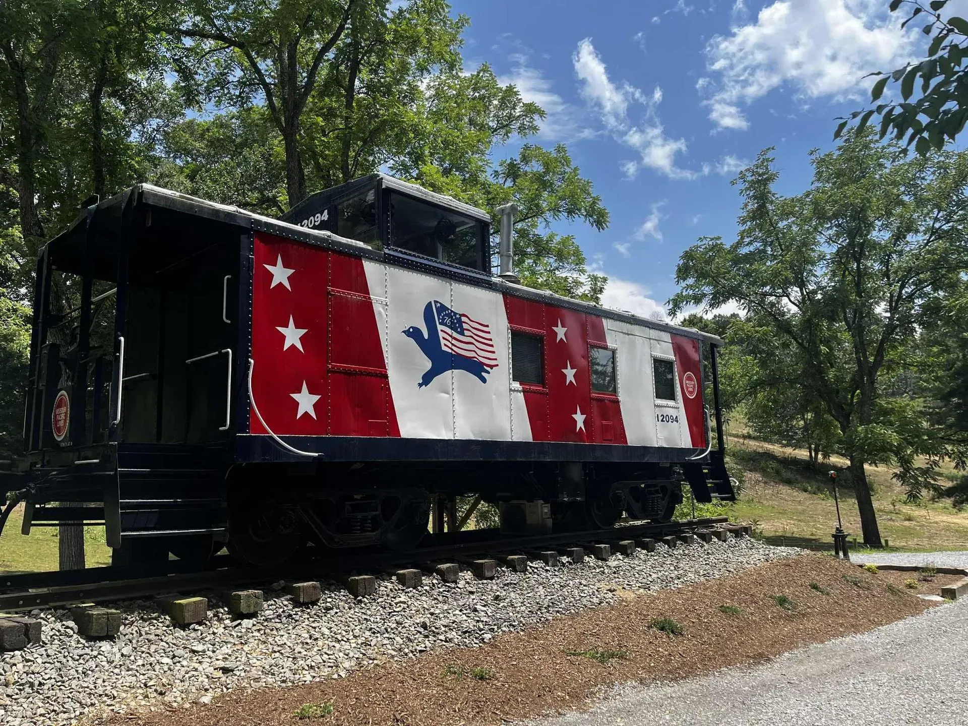 A colorful caboose on tracks, red and white with stars and a flag design.