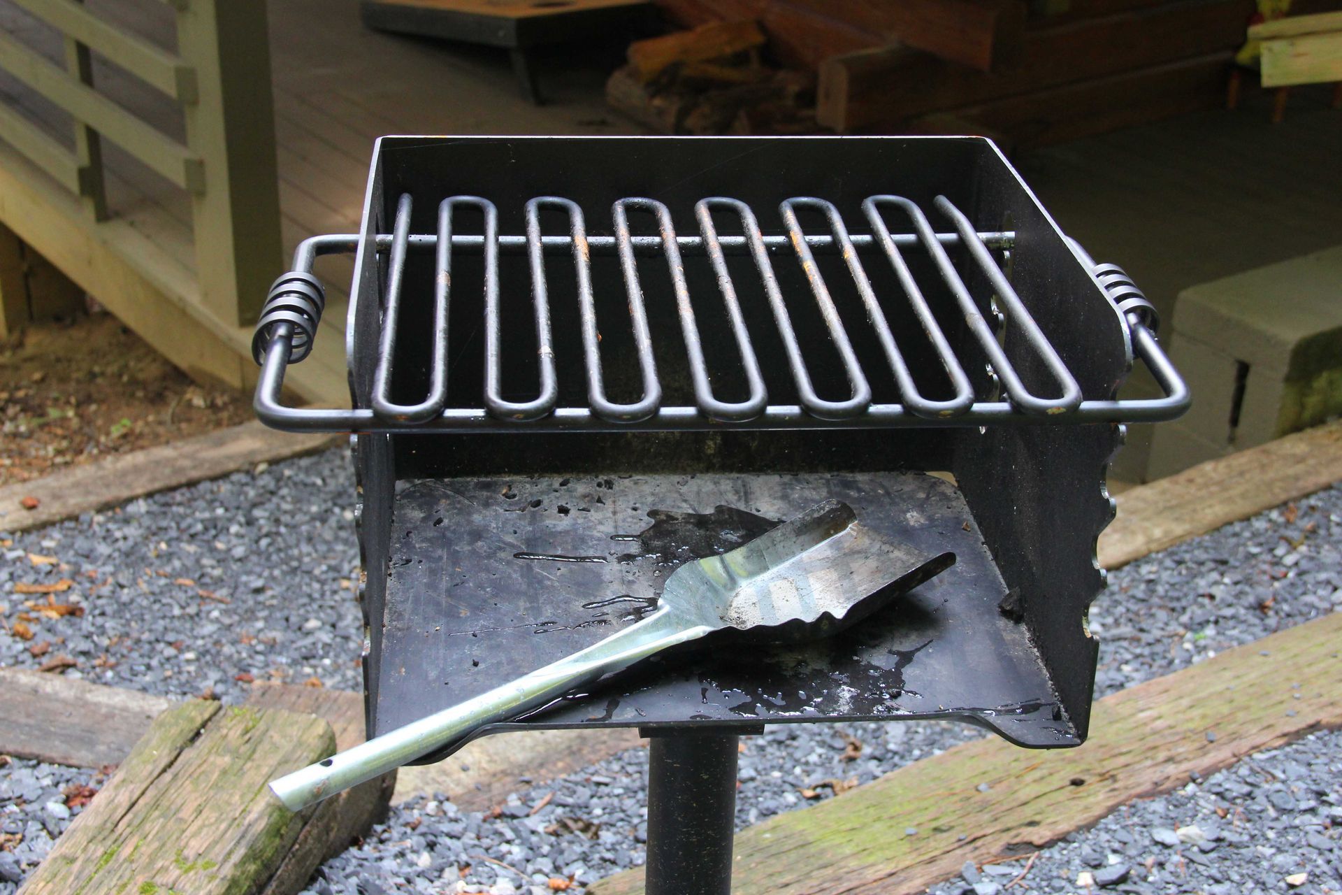Black metal outdoor grill with a spatula.