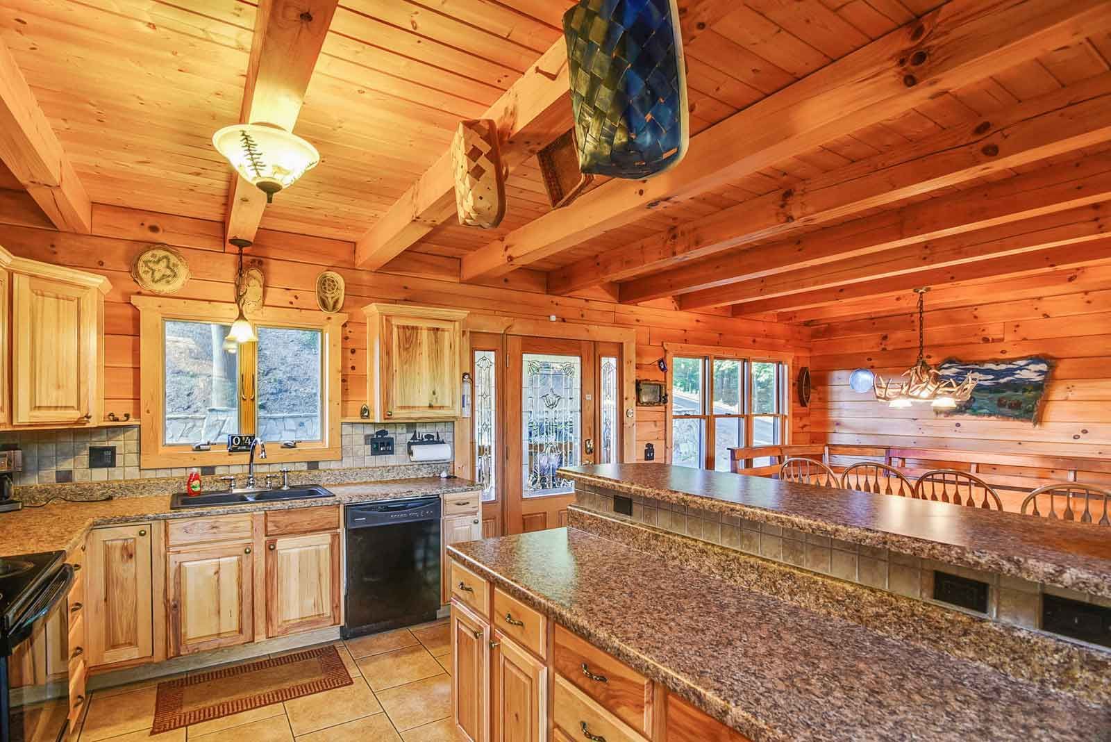Log cabin kitchen with wood cabinets, island, and dining area.