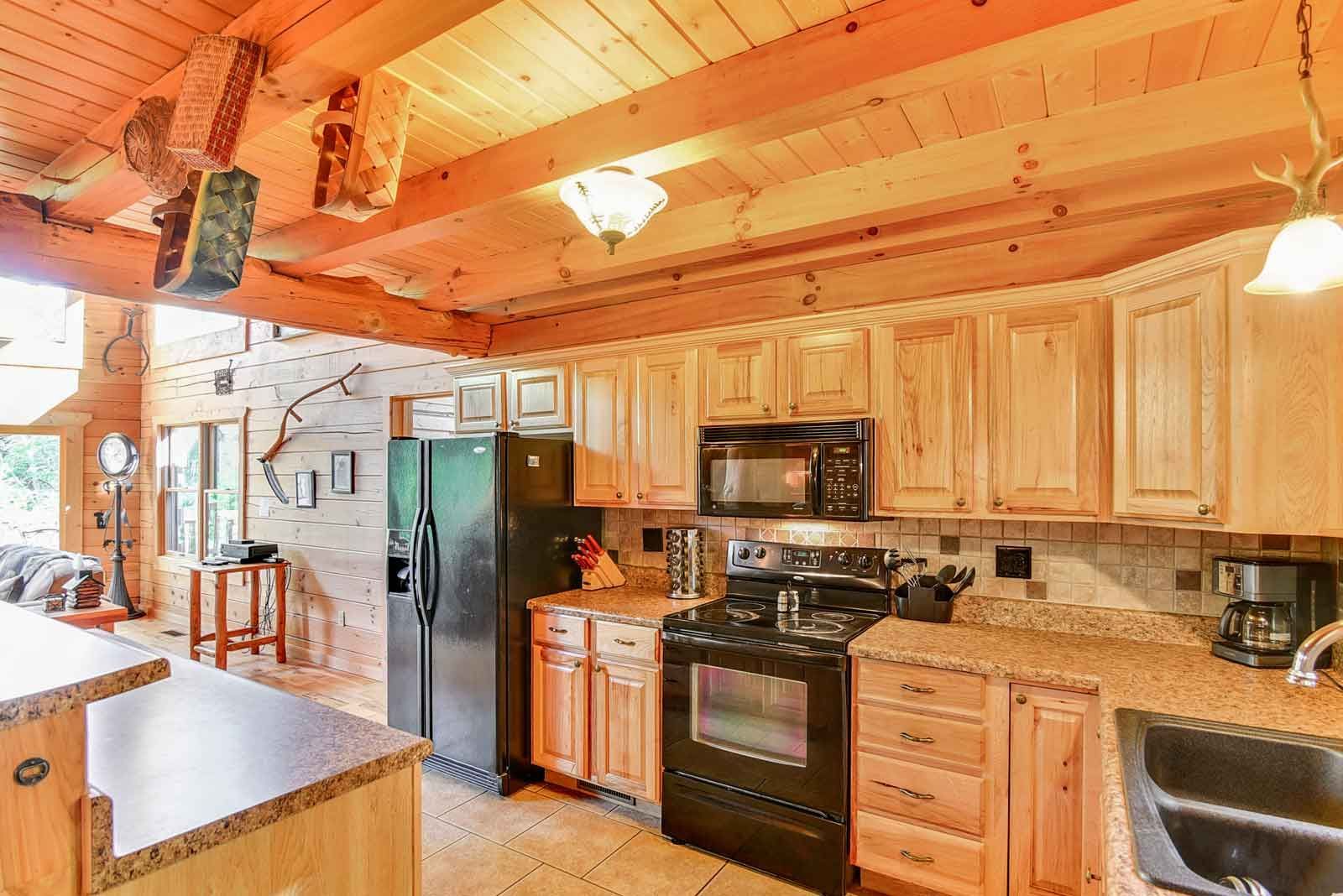 Kitchen with wooden cabinets, black appliances, and light countertops.
