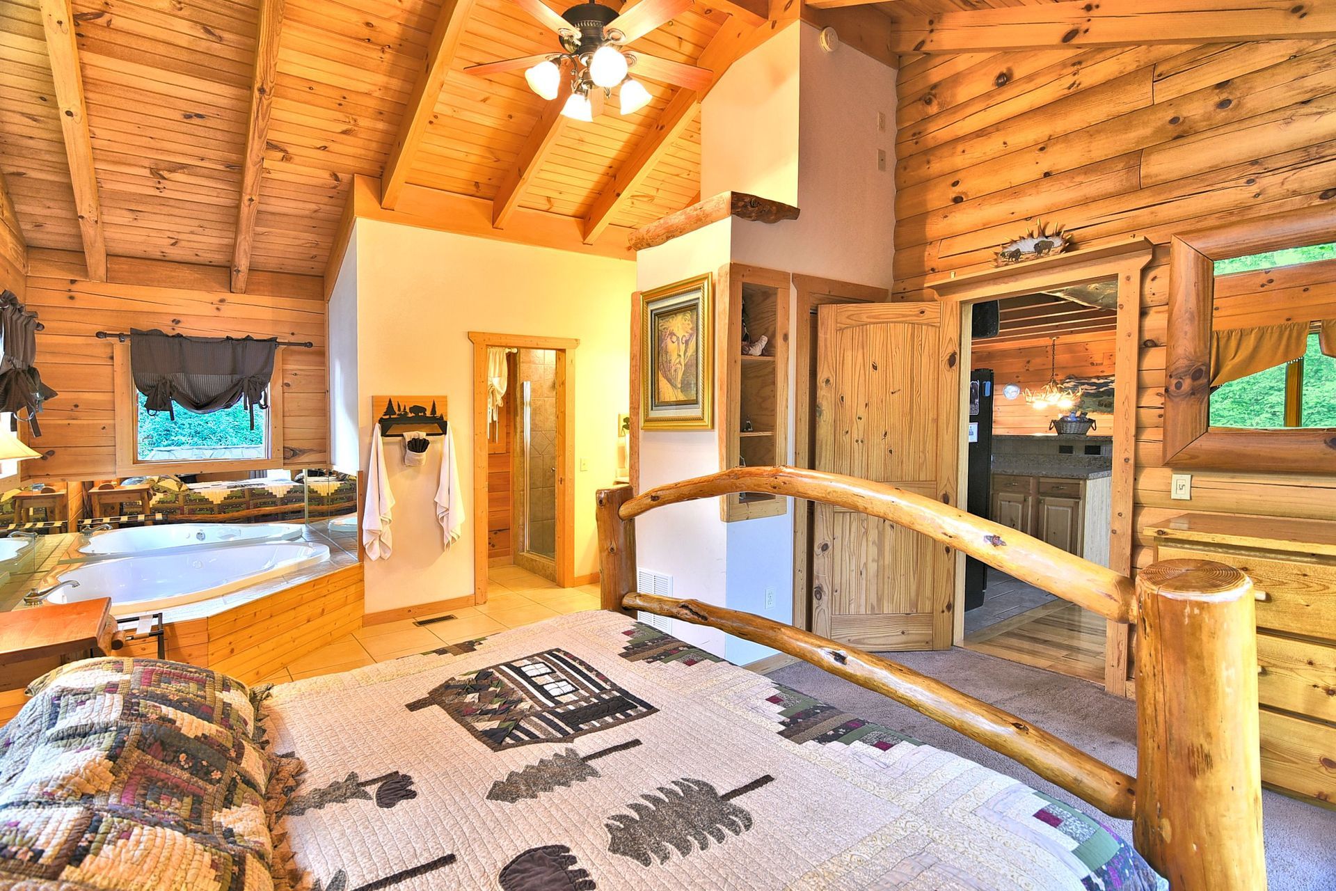 Bedroom with wooden logs, bed with a rustic quilt, and a jacuzzi.