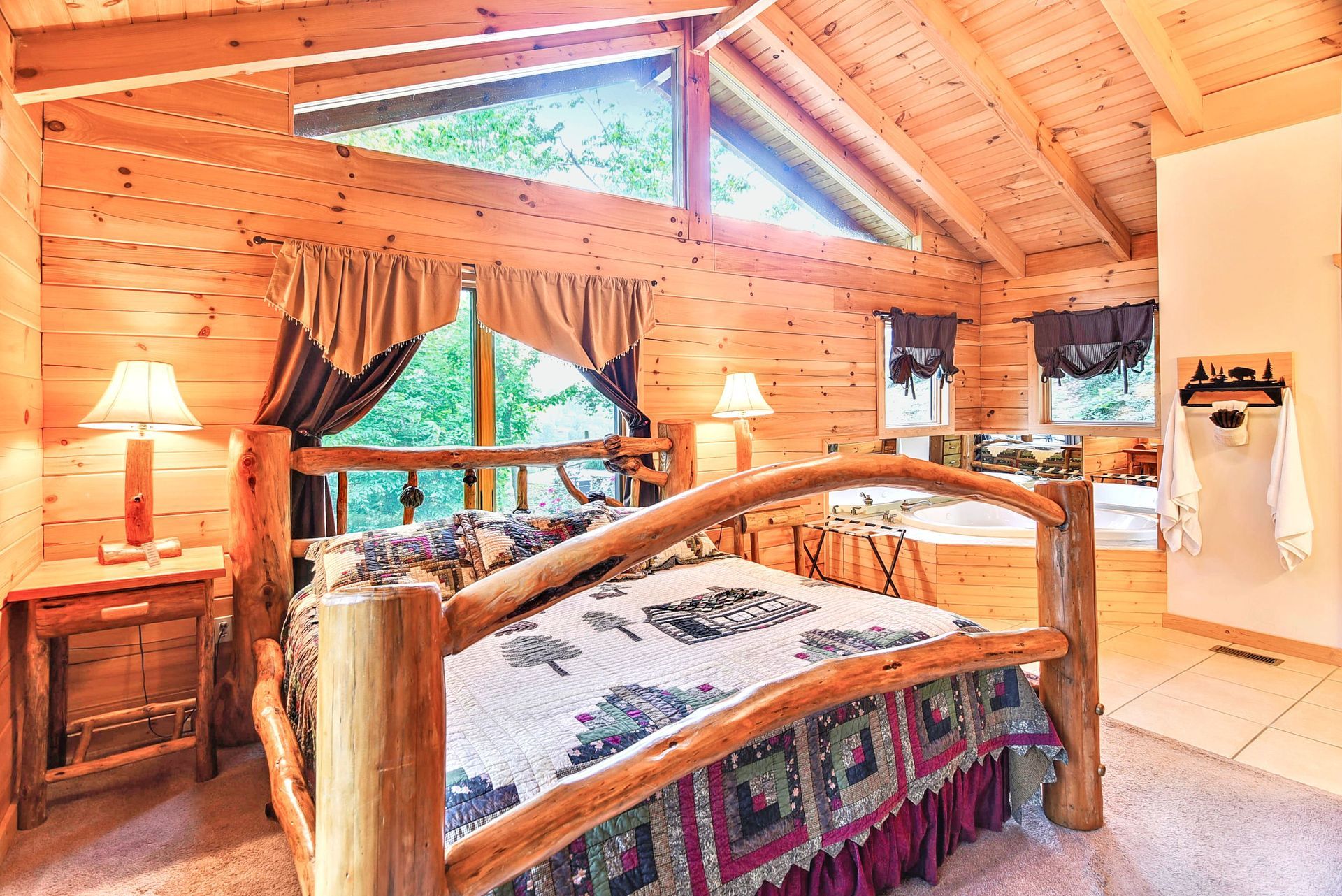 Wooden cabin bedroom with log bed, nightstands, and window overlooking trees.