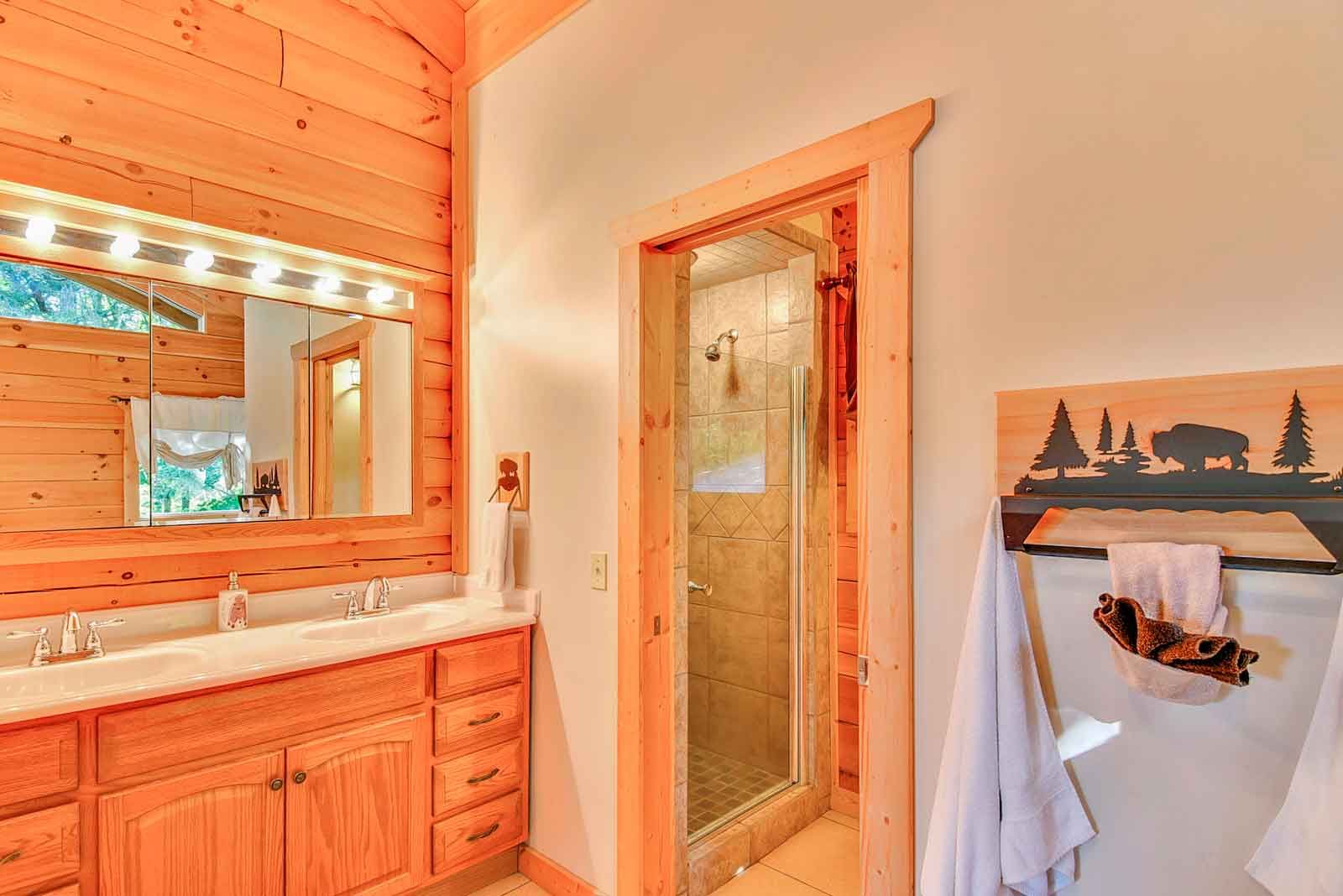Rustic bathroom with wood cabinets, shower, and a towel rack with a bison silhouette.