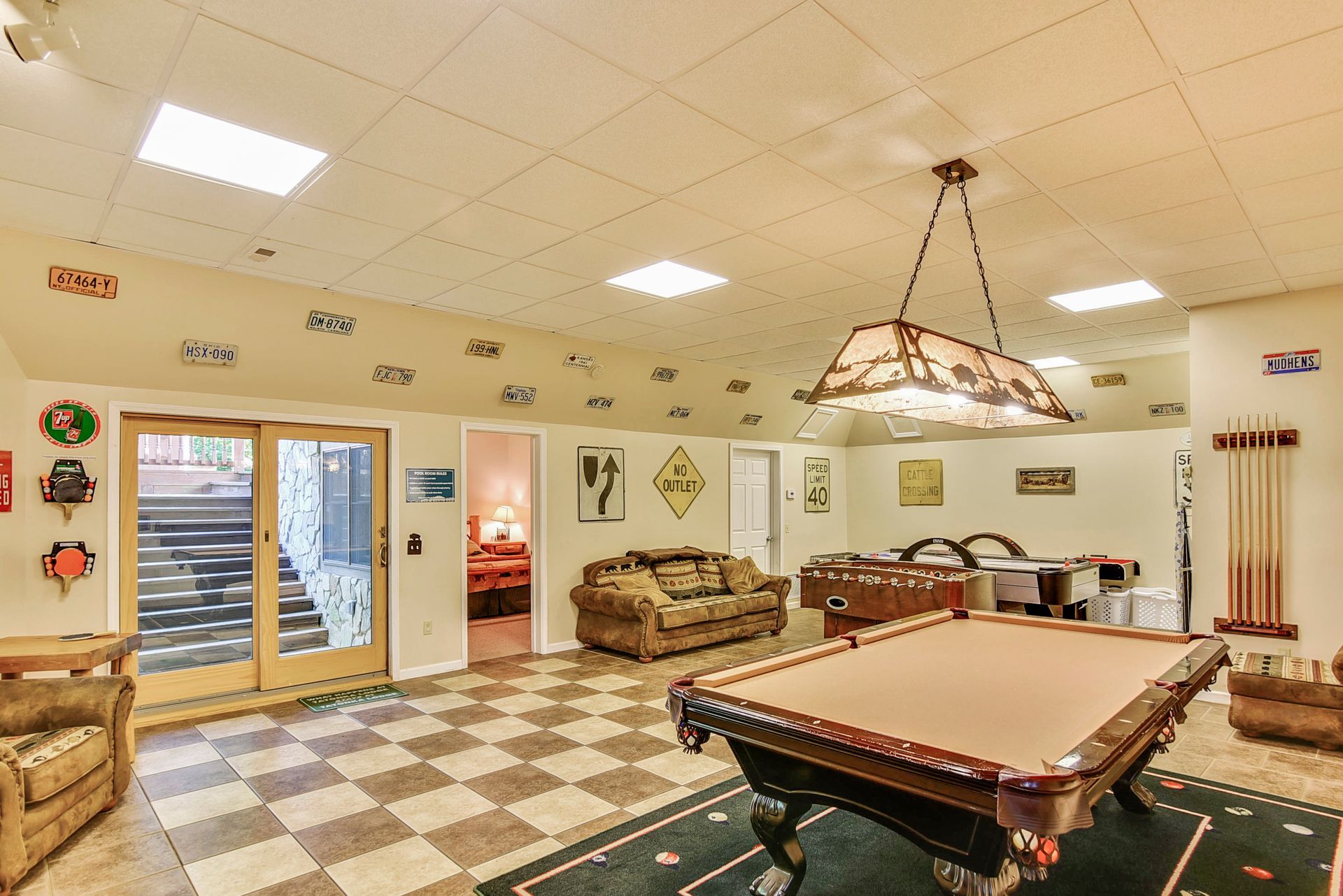 Game room with pool table, foosball, sofa, and license plates on the wall.