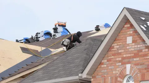 A man is working on the roof of a house.