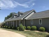 A large house with a gray roof and a driveway leading to it