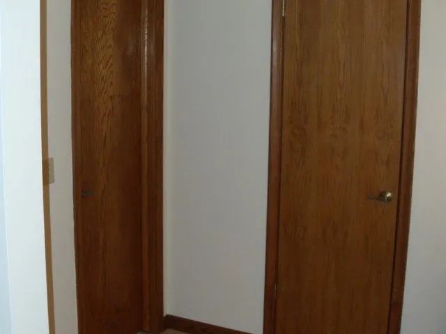 There are two wooden doors in the corner of a room