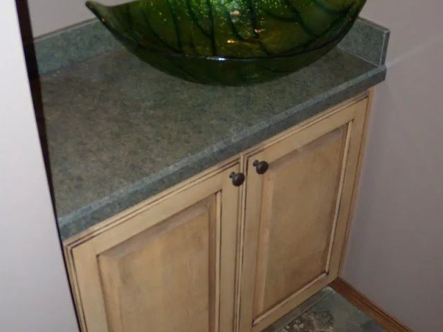 A bathroom sink with a green bowl on top of it