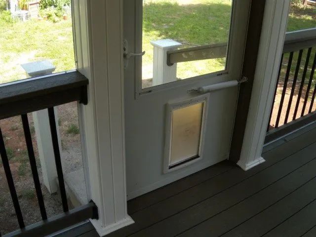 A screened in porch with a dog door and a window
